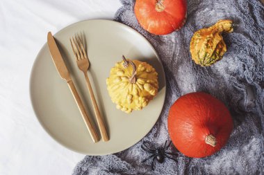 Cadılar Bayramı için sonbahar tatili için akşam yemeği. Kabak, örümcek, gri örümcek ağı ve beyaz arka planda sonbahar dekoru olan mevsimlik masa ortamları. Düz yatış, üst görünüm.