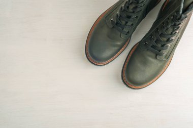 Tahta beyaz arka planda koyu yeşil kadın çizmeleri. Üst görünüm, düz görünüm, kopyalama alanı. Moda ayakkabılar, sonbahar ya da kış ayakkabıları satış mağazası konsepti..