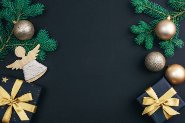 Altın Noel baloları, hediyeler ve siyah arka plandaki süslemeler. Şenlikli düzlük. Üst görünüm, alanı kopyala.