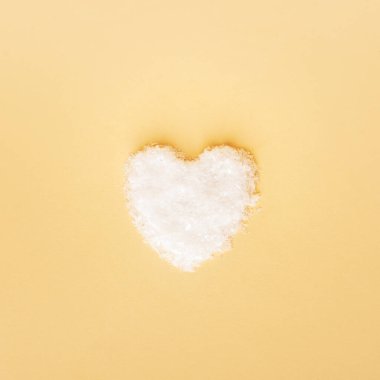 Sarı arka planda kardan yapılmış bir kalp. Sevgililer Günü konsepti. Üst manzara, düz uzanma.