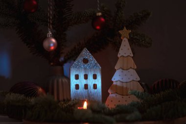 Koyu arkaplanda köknar dallarıyla yanan mum ve ahşap Noel süslemeleri. Noel veya Yeni Yıl tebrik kartı.