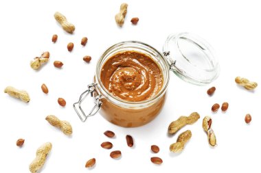 Kavanozda fıstık ezmesi ve beyaz arka planda izole edilmiş fıstık ezmesi. Vejetaryen yemeği. Üst görünüm.