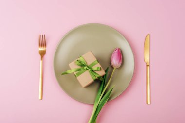 Hediye kutusu ve pembe lale çiçeği açık yeşil tabakta pembe arka planda anneler günü, kadınlar günü konsepti. Üst manzara, düz uzanma.