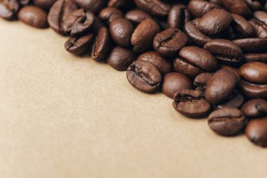 Bej arka planda kavrulmuş kahve çekirdekleri. Yaklaş, boşluğu kopyala.