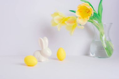 Vazoda sarı laleler ve beyaz arka planda Paskalya süslemeleri. Paskalya konsepti.