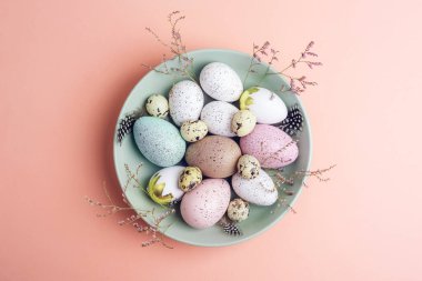 Yeşil tabakta pembe arka planda Paskalya yumurtaları. Üst manzara, düz uzanma.