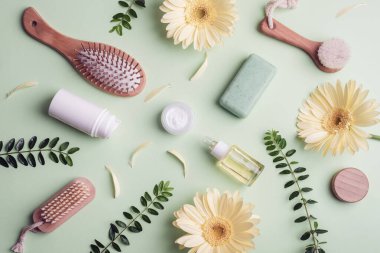 Güzellik ve kaplıca aksesuarları, organik malzemeli kozmetik arka plan, cilt ürünleri ve yeşil arka planda sarı gerbera çiçekleri. Üst manzara, düz uzanma.