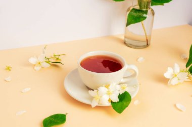 Bir fincan çay ve bej masadaki yasemin çiçekleri. Yakın çekim..