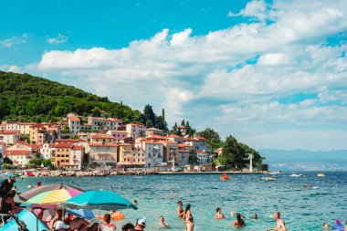 Moscenicka Draga Hırvatistan - 30 Haziran 2024: Güneşli bir yaz gününde yüzen insanlarla dolu plaj.