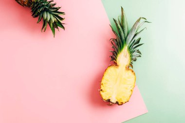 Pembe ve yeşil arka planda yarım ananas. Sağlıklı yemek, yaz konsepti. Üst görünüm, düz görünüm, kopyalama alanı.