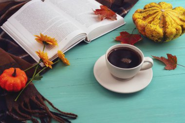 Kahve fincanı, balkabağı, sonbahar yaprakları ve mavi ahşap masa üzerine kitap. Sonbahar, Şükran Günü konsepti. Üst görünüm.