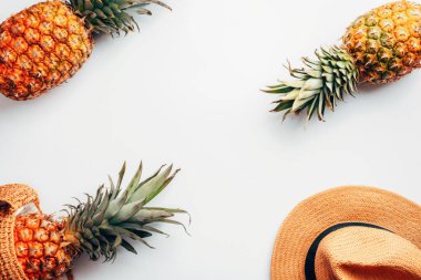 Kadınların yaz aksesuarları, beyaz arka planda şapka ve ananaslar. Güzellik, moda, yaz tatili konsepti. Üst görünüm, düz görünüm, kopyalama alanı.
