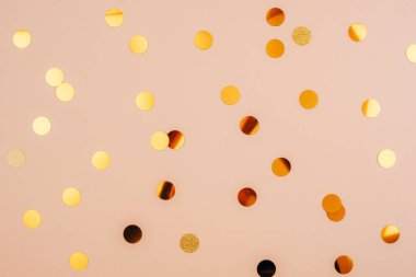 Altın konfeti yumuşak bej arka planda dağınık, üst manzara.