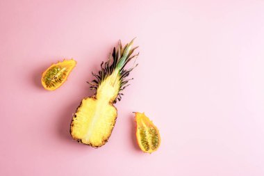 Ananas ve kiwano meyvesi pastel pembe arka planda yaratıcı bir şekilde düzenlenmiştir. Üst görünüm, düz görünüm, kopyalama alanı.