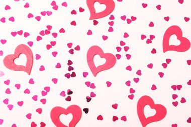 Pembe kalpler ve konfeti minimalist bir şekilde ışık arka planına saçılmış. Sevgililer Günü konsepti. Üst manzara, düz uzanma.