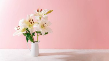 Pastel pembe arka planda seramik vazoda yumuşak gölgeli beyaz zambaklar..
