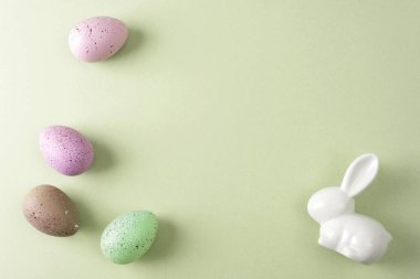 Benekli Paskalya yumurtaları ve yeşil arka planda beyaz tavşan. Üst görünüm, düz görünüm, kopyalama alanı.