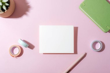 Pembe kalemli beyaz kart ve pastel pembe arka planda gölgeli washi bandı. Üst görünüm, düz görünüm, model.