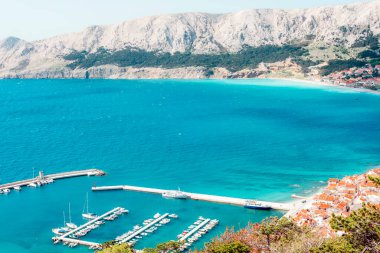 Turkuaz deniz manzarası, liman ve kıyı kasabası yakınlarındaki dağlı tekneler. Baska kenti manzarası, Krk Adası, Hırvatistan.