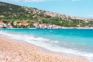 Çakıl taşlı sahil ve turkuaz deniz kenarında renkli evleri olan bir sahil kasabası. Baska kenti manzarası, Krk Adası, Hırvatistan.