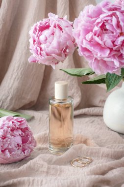Kumaş dokusuna karşı parfüm şişesi ve şakayık çiçekleri..