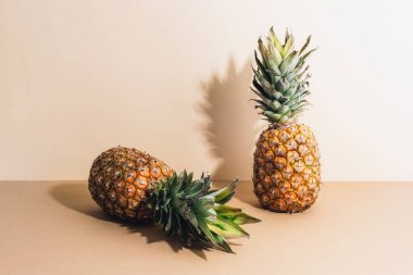 Bej arka planda iki taze ananas ve sert gölgeler..