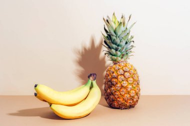 Taze ananas ve arka planda koyu gölgeli bir demet muz..