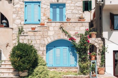 Akdeniz tarzı turkuaz panjurlu taş binanın güzel cephesi.