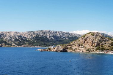 Kristal mavi deniz ve dağlarla Baska şehri manzarası. Krk Adası, Hırvatistan.