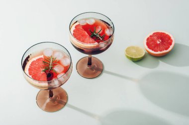İki ferahlatıcı kokteyl greyfurt dilimleri, buz küpleri, arka planda biberiye ve limon, yaz içeceği konsepti..