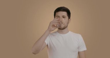 Ağız hijyeniyle ilgilenen neşeli genç bir adam. Adamın biri evinin banyosunda diş etlerini ve dişetlerini özel hijyen suyuyla temizliyor. Kişisel sağlığını ve iyiliğini önemseyen bir adam.