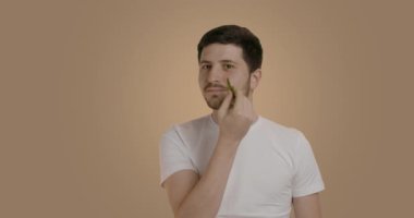 Genç bir adam kırışık bir taşla derisini geriyor. Yüz tedavisinden sonra, adam kırışıklıkları azaltmak için aletlere masaj yapar. Profesyonel dermatolojik prosedürler kavramı