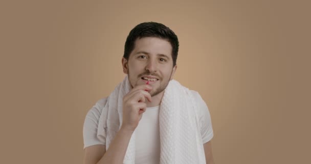 鏡面カメラで白いタンクトップを身に着けて完璧な肌を持つ幸せな若い男は 歯間ブラシで彼の歯をブラッシング ベージュの背景 スタジオの肖像画 介護方法の概念 — ストック動画