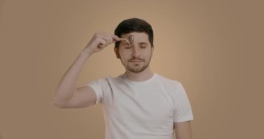 Sağlıklı, taze ve yakışıklı sakallı bir erkek modelin portresi. Alnına yüz maskesi ile masaj yapıyor. Genç adam sabah rutinini uyguluyor. Adamın güzelliği. Cilt bakımı.