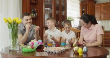 Mutlu aile, mutfakta paskalya yumurtası boyuyor.