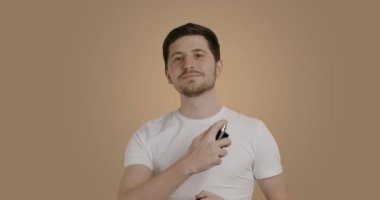 Morning of the groom and perfume spray. Handsome man chooses perfume. Happy man on his wedding day using cologne. The groom gets ready the morning before the wedding ceremony