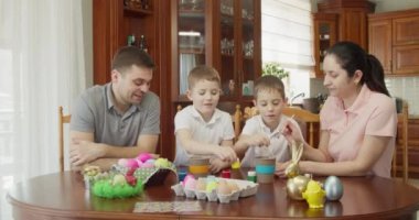 Mutlu aile, mutfakta paskalya yumurtası boyuyor.