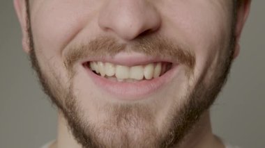 Beautiful natural smile close-up of a bearded man. Young and happy man smiling at the camera. Clean skin, natural teeth, clean and straight. Concept for dental and orthodontic treatments
