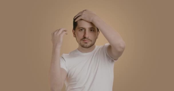 留着黑发胡子的男人用胶水固定头发 穿着白色背心的年轻人在浴室里做他的仪容打扮 一个面带笑容准备工作的人 — 图库视频影像