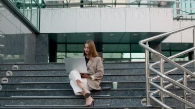 Modern bir bilgisayar üzerinde çalışırken modern bir avukatlık bürosunun önünde oturan bir kadın avukat. Klasik giyinmiş ve stil sahibi kadın internet müşterilerine danışmanlık yapıyor. İş kadını