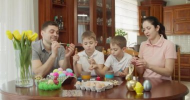 Mutlu aile, mutfakta paskalya yumurtası boyuyor.
