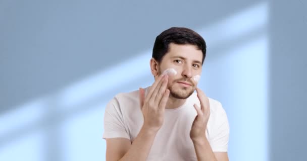Adulto Jovem Aplicando Hidratante Pele Facial Enquanto Olha Espelho Banheiro — Vídeo de Stock
