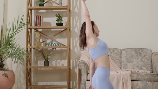 一个漂亮迷人的亚洲女人正在练习瑜伽 朝上面对着狗的姿势 她的镇定沉着 女人穿着腿和上衣 做伸展运动 在家里的客厅里 — 图库视频影像