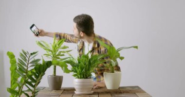 Çiçekçi dükkanında eşiyle seçeceği yeşil çiçeklerle selfie çekerken mutlu bir müşteri. Yakışıklı adam yeniden dikilen çiçeklerin resimlerini çekiyor ve güzel görünüyorlar..