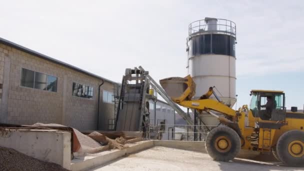 在水泥厂 一辆黄色的工业起重机卸下了前面拖着拖车的沙子和砾石 水泥搅拌的地方在混凝土搅拌机后面 水泥厂的工作过程 — 图库视频影像