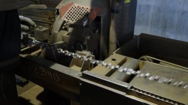 İnşaat malzemeleri üssünden bir işçinin profesyonel ve yüksek performanslı bir aletle demirleri keserken yakın plan görüntüsü. Metal bir barda, bir işçi özel ekipmanla parmaklıkları keser.