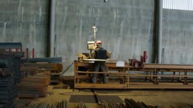 Düzgün donanımlı bir işçi, profesyonel ve yüksek performanslı bir cihazla takviyeleri kesiyor. Metal parmaklıkların dibinde, bir işçi onları özel ekipmanların yardımıyla kesiyor..
