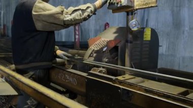 İnşaat mühendisi işçiler metal bir depoda demir ve demiri kesiyorlar. Metali robot bir aletle kesen işçiler.
