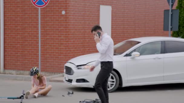 交通事故の後 動揺し怖がった車の運転手は 救急車 保険会社に電話しようとします 保護ヘルメットを着用した電動スクーターで女性を殴った男性 — ストック動画