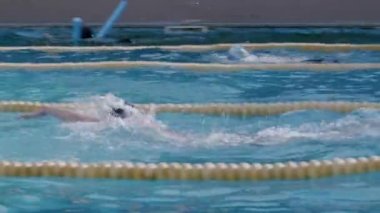 Yüzücü ön emekleme tekniğini uyguluyor. Spor ve dayanıklılık teması. Havuzda profesyonel yüzücülerle yüzme yarışı, en güçlü ve en hızlı olan kazanır. Sporcular şampiyonada yarışıyorlar.